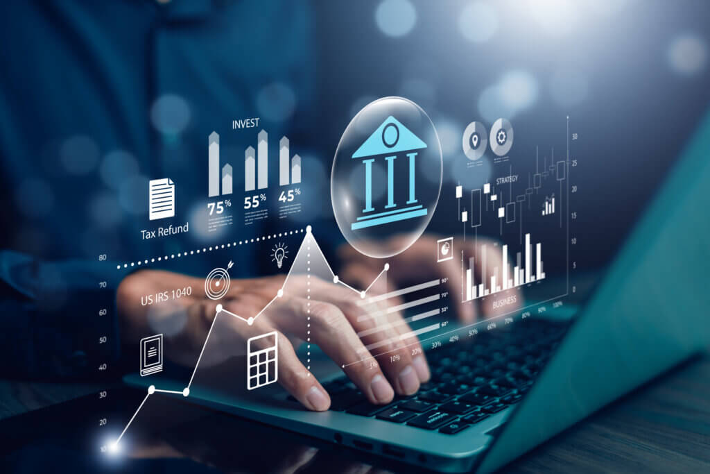 Government A person’s hands typing on a laptop, with financial and investment data projected onto the screen, including graphs, charts, a tax refund icon, and a symbol of a bank.