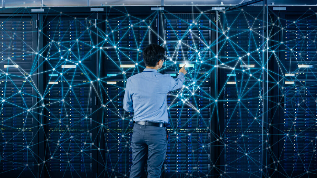 Retail 1 A person in a blue shirt interacting with a data server, with digital lines and connections illustrating a network within the server room.