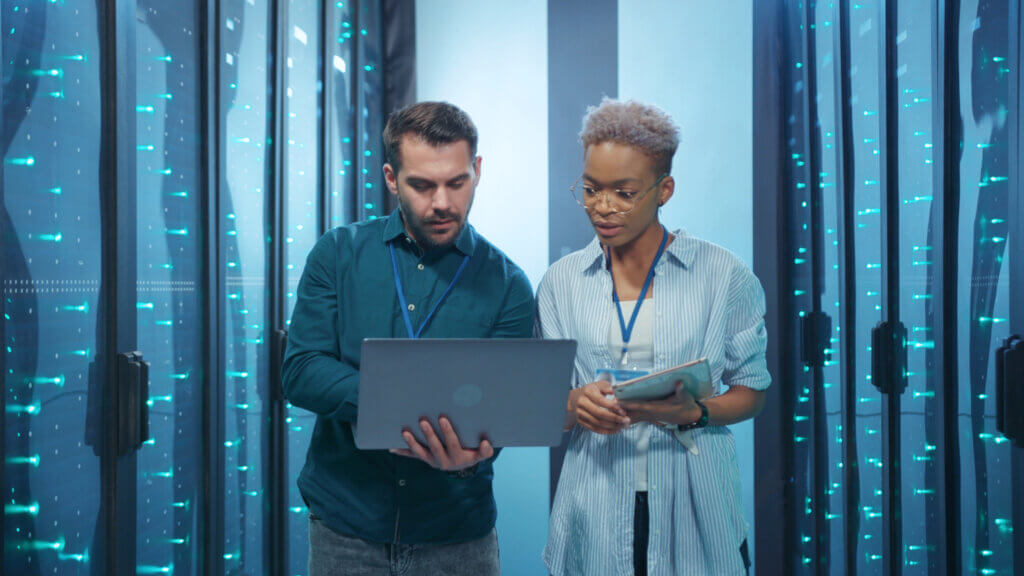 Healthcare 1 Two professionals collaborating on a laptop inside a data center.